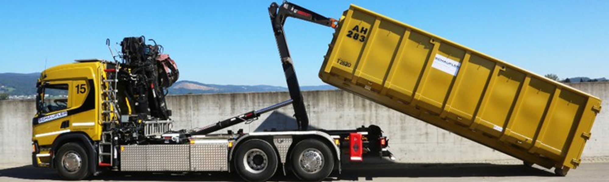 Abrollkipper mit Frontkran beim Austausch eines Abrollcontainers